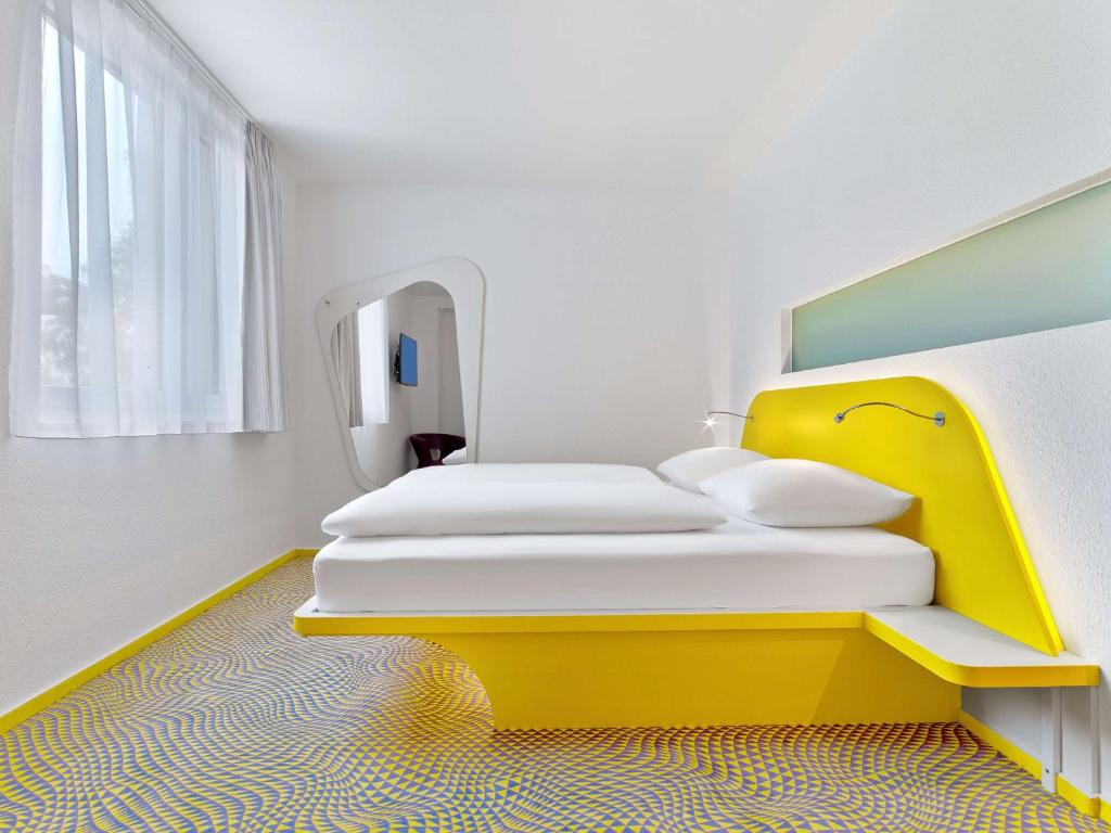a bedroom with two beds and a yellow headboard at prizeotel Hannover-City in Hannover