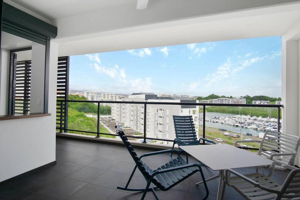 a balcony with a table and chairs and a large window at Appartement Corail Bleu in Fort-de-France