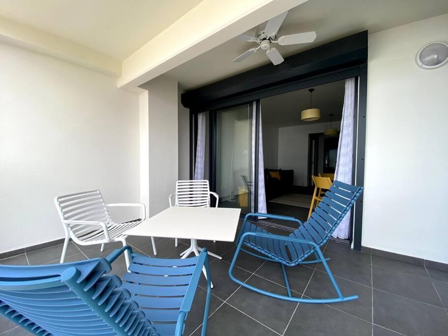 a patio with blue chairs and a white table at Appartement Corail Bleu in Fort-de-France