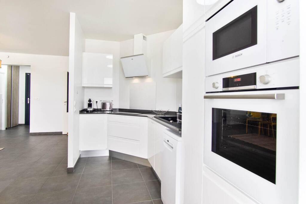 a white kitchen with white cabinets and a microwave at Appartement Corail Bleu in Fort-de-France