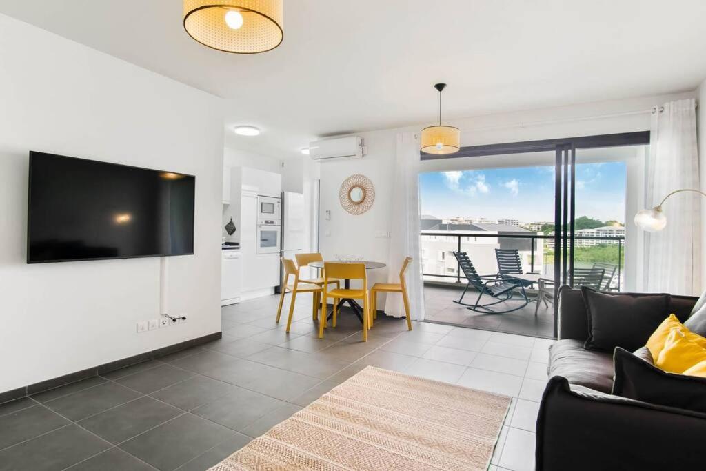 a living room with a couch and a table with chairs at Appartement Corail Bleu in Fort-de-France