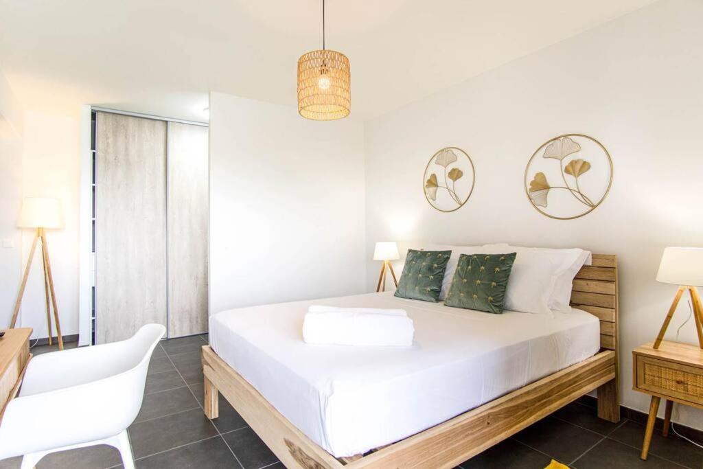 a bedroom with a white bed and a white chair at Appartement Corail Bleu in Fort-de-France