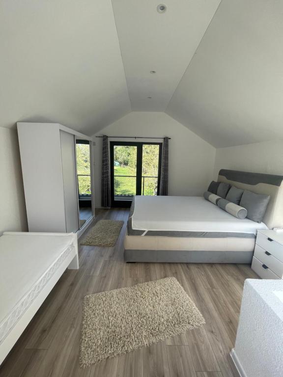 1 dormitorio con 1 cama blanca grande y suelo de madera en Vikendica u prirodi na ranču, en Zolaći