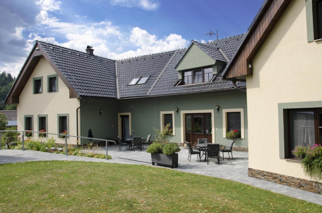 ein Haus mit Terrasse und Rasen in der Unterkunft Apartmány pod lípou in Horní Heřmanice