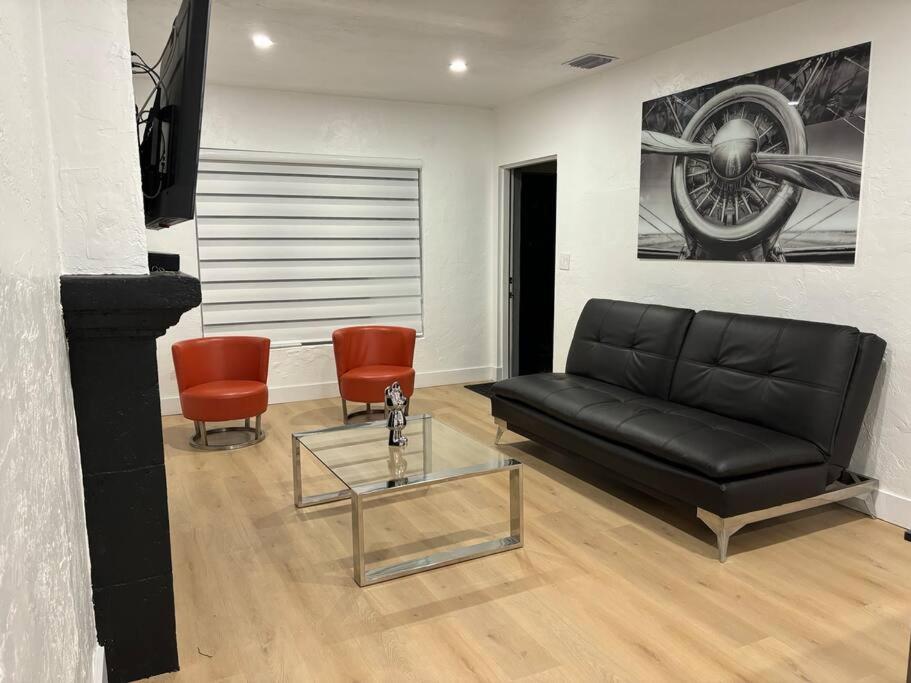 - un salon avec un canapé noir et deux chaises orange dans l'établissement Sri House, à Miami