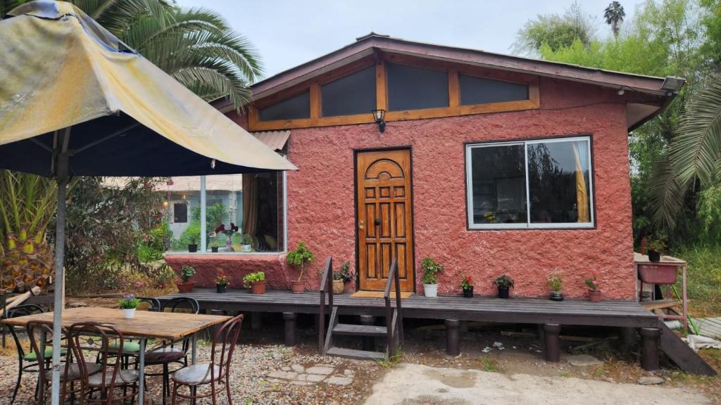 een klein huis met een tafel en stoelen en een parasol bij Cabañas Tronco viejo in La Serena