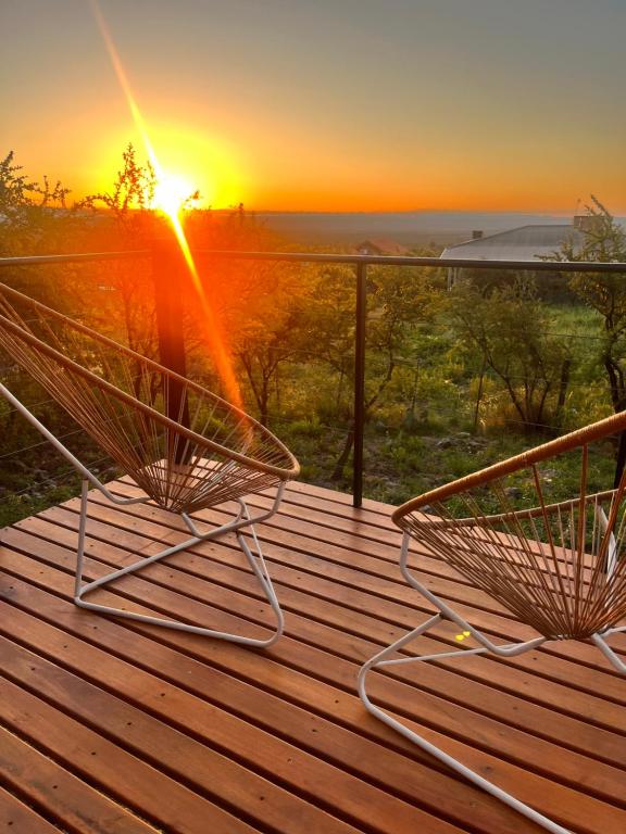 two benches on a deck with the sunset in the background at Flor Silvestre in Carpintería