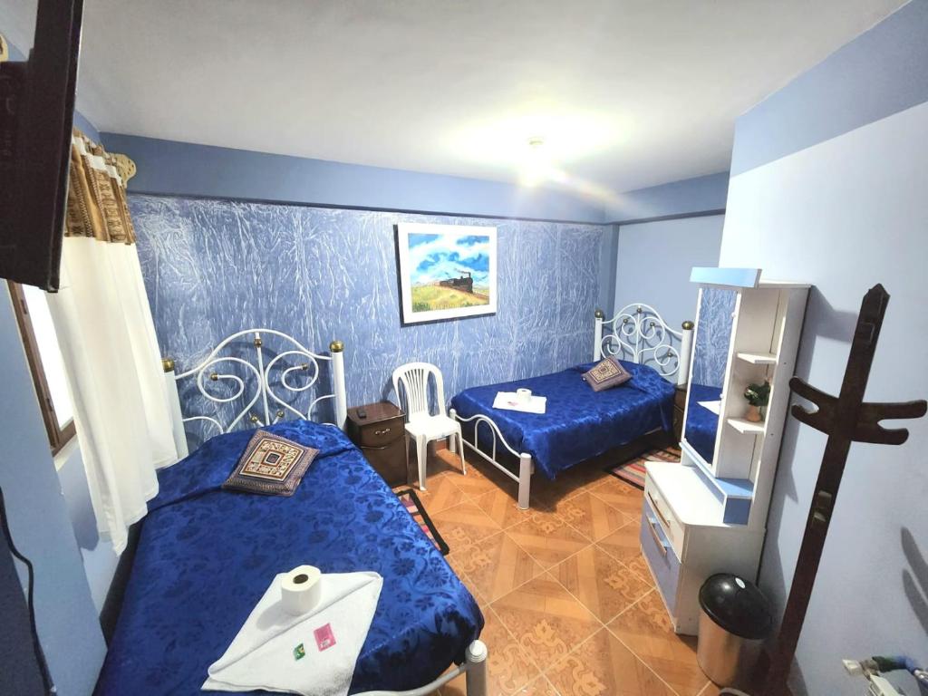 a blue room with two beds and a mirror at Hotel Aguilar in Uyuni