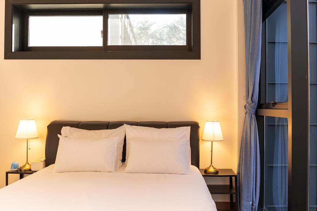sypialnia z łóżkiem z białymi poduszkami i oknem w obiekcie Private Pool Villa with filled with stars w mieście Ulsan