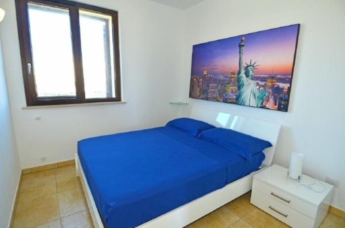 レウカにあるAttico del sole e del mareの青いベッドと自由の像の写真が備わるベッドルーム1室
