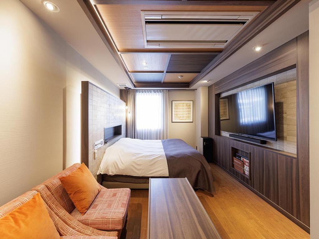 a bedroom with a bed and a tv and a couch at Y-HOTEL - Vacation STAY 22328v in Hiroshima