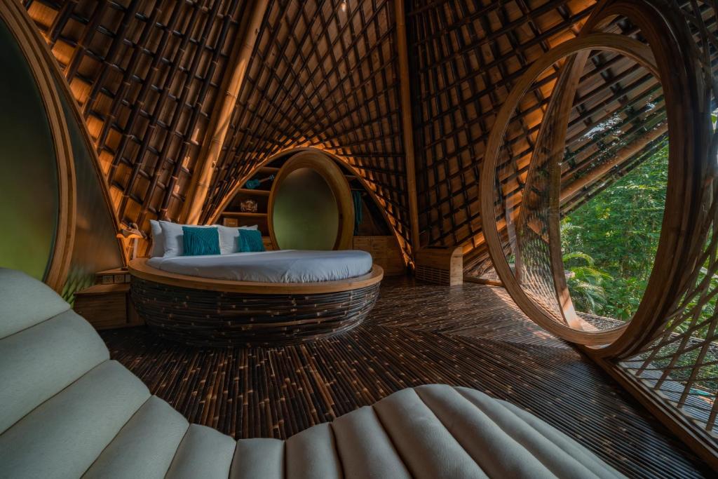 Suenyo Eco Retreat في تابانان: غرفة مع سرير مستدير في منزل من الخيزران