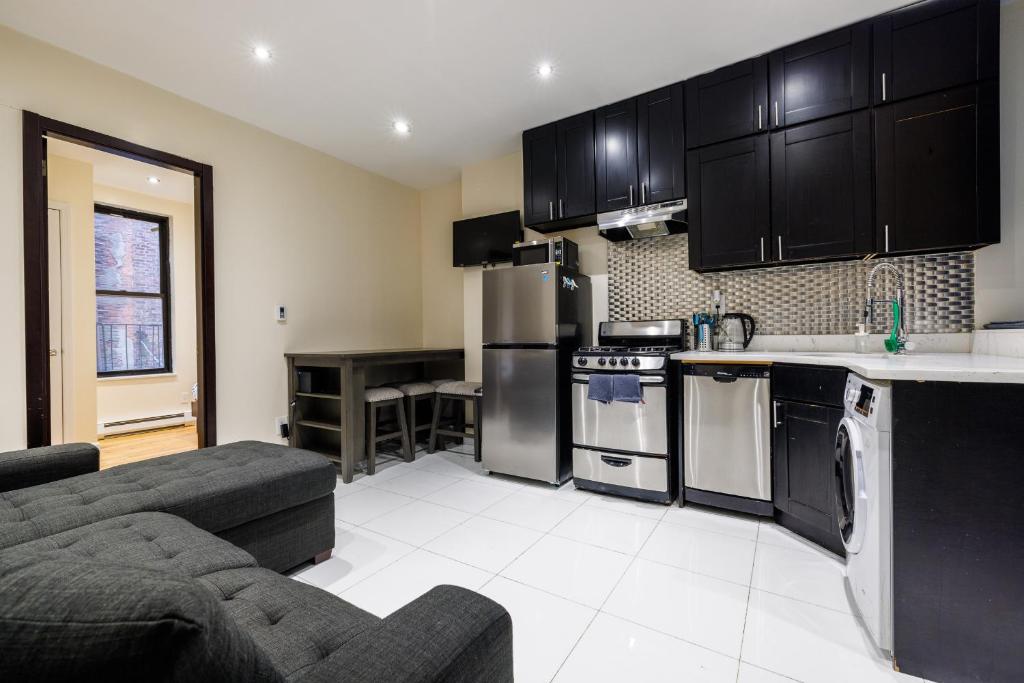 uma cozinha e sala de estar com armários pretos e um sofá em Discover the Comfort of Columbia University Area em Nova York