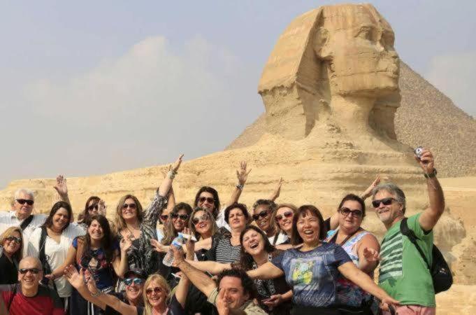 Un groupe de personnes posant devant une statue dans l'établissement Khufu Pyramids Hotel, au Caire
