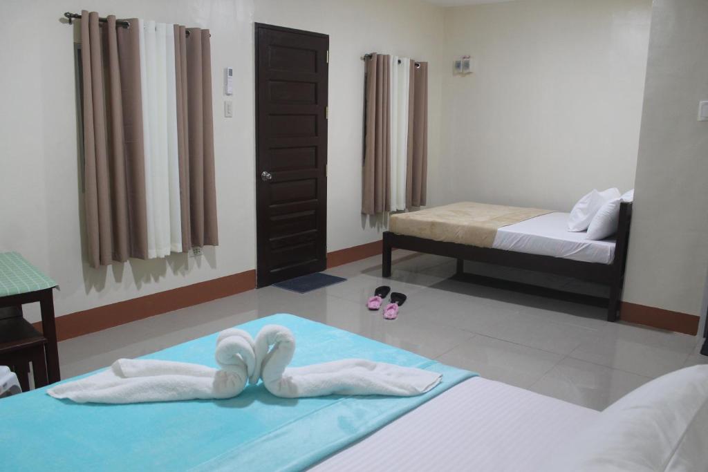 1 Schlafzimmer mit 2 Betten und Handtüchern auf dem Boden in der Unterkunft JUNLYN APARTELLE in Panglao