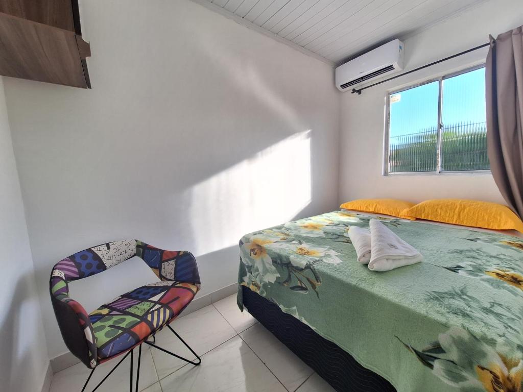1 dormitorio con 1 cama y 1 silla en Mar.4: above-store with balcony near Airport and Stella Maris beach en Salvador