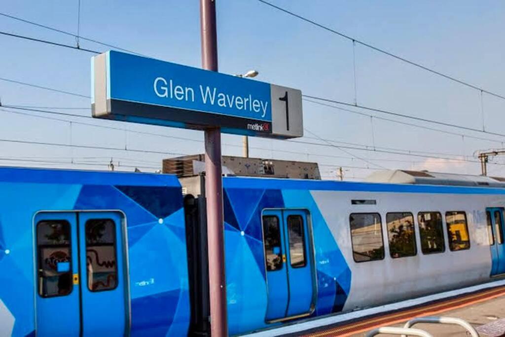 un tren azul y blanco sentado en una estación de tren en 5 BR & 3 BTH House in Outlook Glen w/ 2 car parks, en Glen Waverley