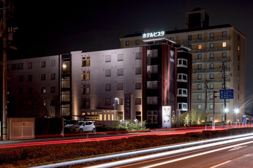 a building with a sign on top of it at night at Hotel Vista Kumamoto Airport in Ozu