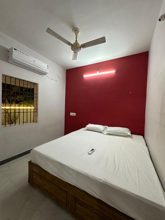 - une chambre avec un grand lit et un mur rouge dans l'établissement Arunachala Sashwin Guest House, à Tiruvannāmalai