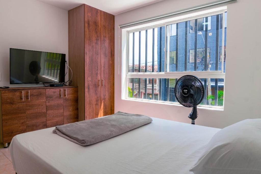 a bedroom with a bed with a fan and a window at Cómodos apartamentos cerca al metro de Medellín in Medellín