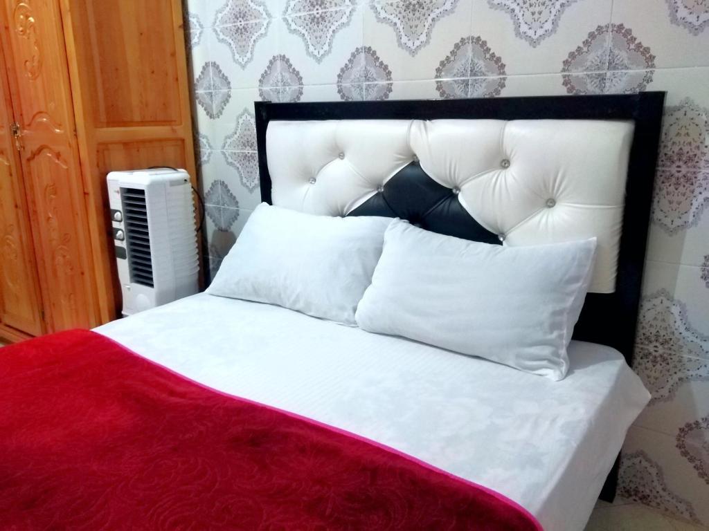 un letto con coperta rossa e cuscini bianchi di Aziz House 2 a Tan-Tan