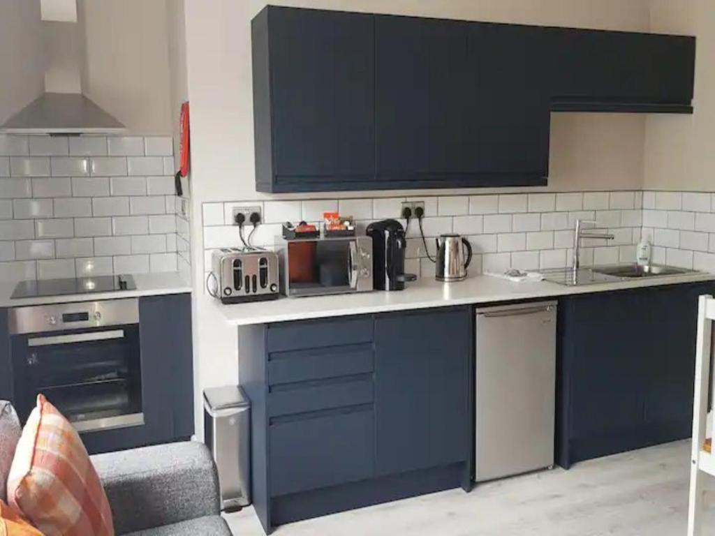 - une cuisine avec des placards bleus et un évier dans l'établissement Pass the Keys Superb 1st Floor Town Centre Apartment Refurbished, à Grimsby