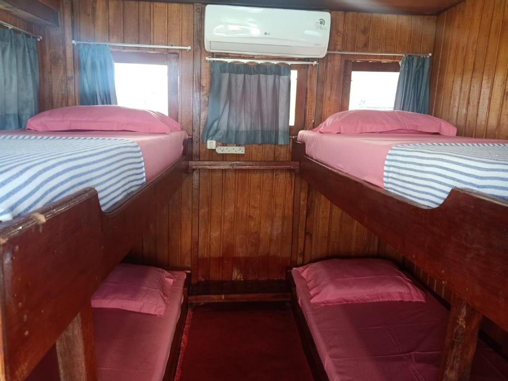 2 łóżka piętrowe w niewielkim pokoju z oknami w obiekcie Open Trip Komodo 3D2N w Labuan Bajo