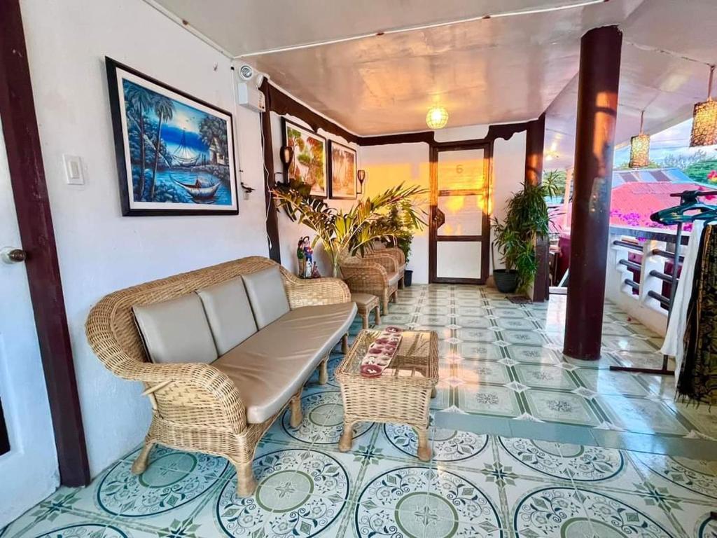 a lobby with wicker chairs and a table on a tile floor at Seaside Hostel Malapascua in Malapascua Island