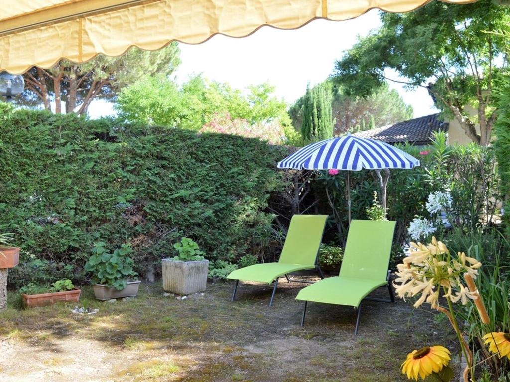 - deux chaises vertes et un parasol dans la cour dans l'établissement Appartement 2 pièces cabine avec terrasse, jardin, piscine et parking, proche plage - Le Lavandou - FR-1-251-517, au Lavandou