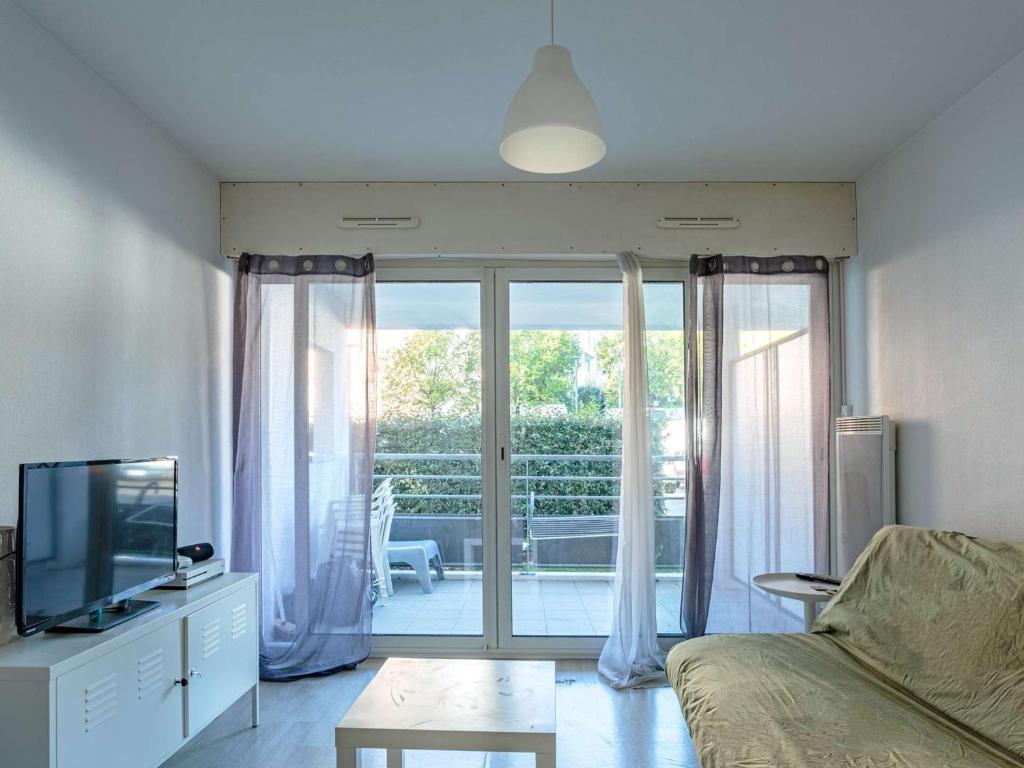 uma sala de estar com uma televisão e uma porta de vidro deslizante em Appartement Anglet, 1 pièce, 2 personnes - FR-1-3-600 em Anglet