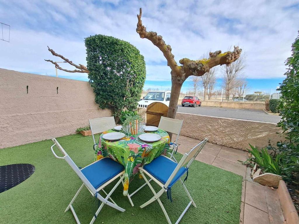 une table, deux chaises et un arbre sur une pelouse dans l'établissement Appartement cosy 2 pièces - jardin privé, accès direct plage, animaux acceptés ! - FR-1-326-801, à Marseillan