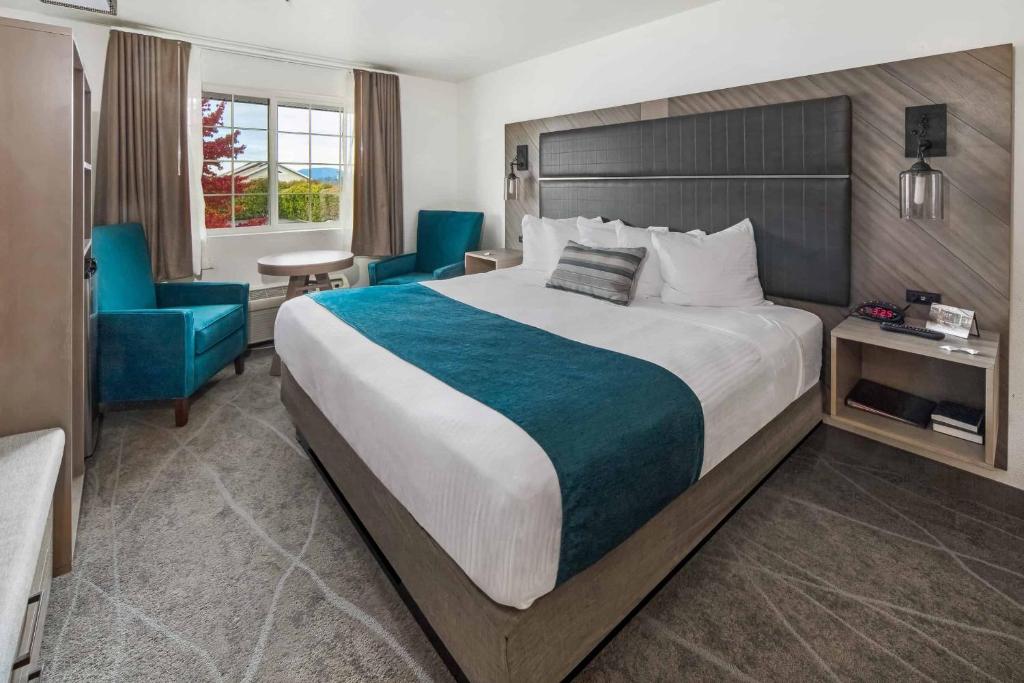 een hotelkamer met een groot bed en blauwe stoelen bij The Marina Inn in Anacortes