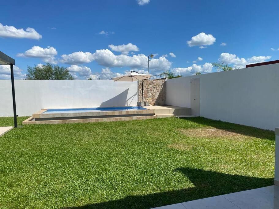 een tuin met groen gras en een witte muur bij Alquiler de Casa en San Bernardino ::: 1.500.000 Gs. por día in Ypacarai