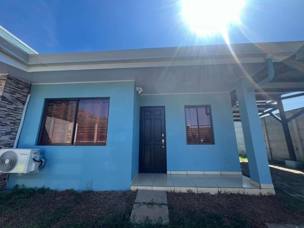 ein blaues Haus mit schwarzer Tür und Sonne in der Unterkunft Hassan House in San José