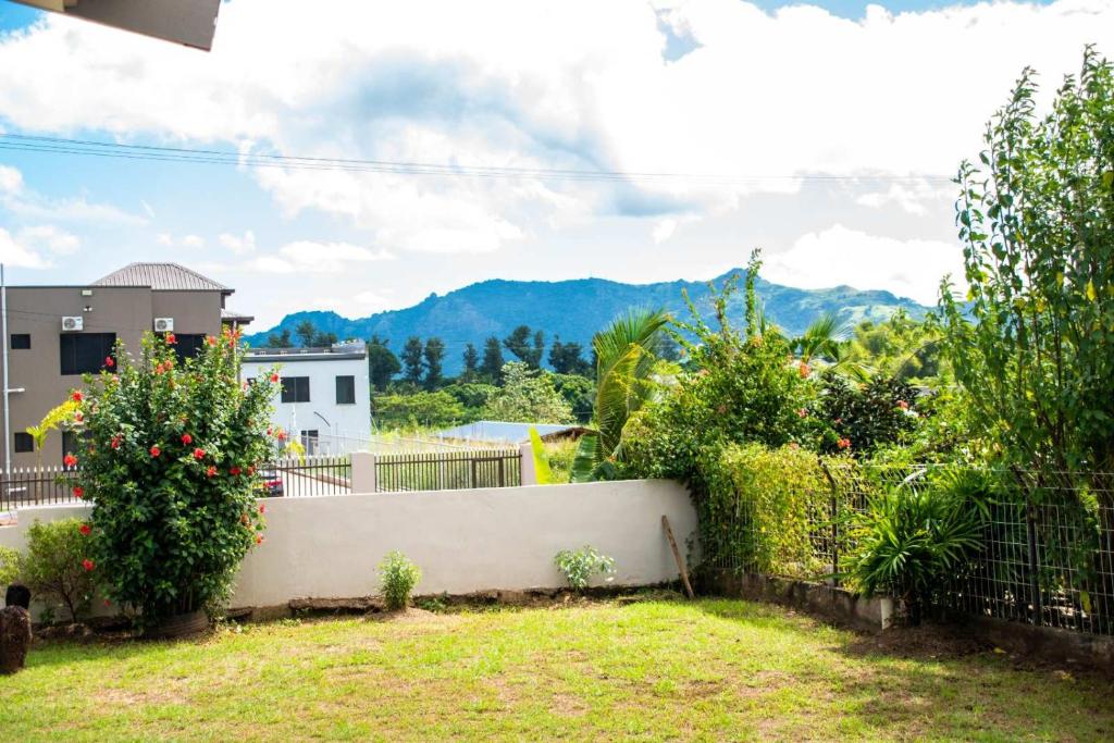 a garden with a fence and some plants and mountains at Family Homestay in Nadi