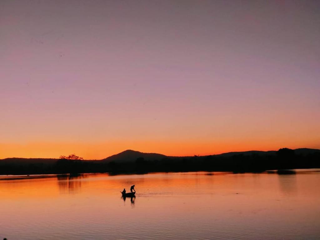 a person riding a horse in a lake at sunset at Ranjo's Farm house in Chāmrājnagar