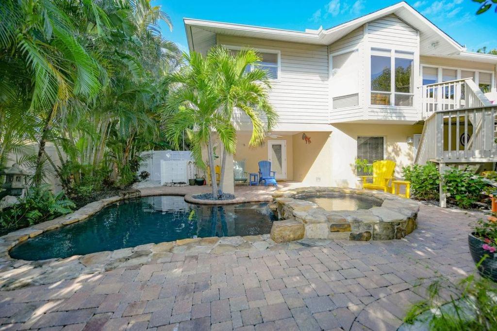 a house with a swimming pool in front of a house at La Buena Vida - Bright Beachy Canal Front Steps to Beach PoolSpa Dock Beach Gear Dogs OK in Anna Maria