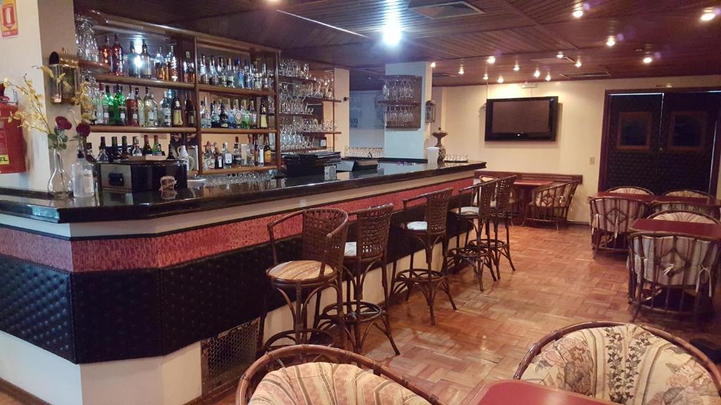 un bar con un montón de taburetes en una habitación en Cristal Executive Hotel, en Francisco Beltrão