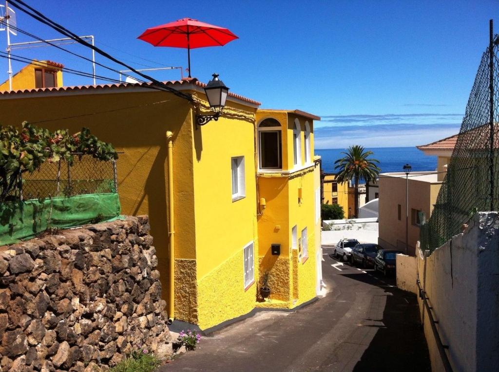 a yellow building with a red umbrella on top of it at Casa Dominica in La Guancha