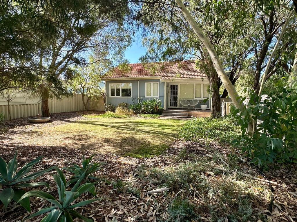 una casa con un patio con árboles delante de ella en Barefoot Beach Cottage, en Geographe