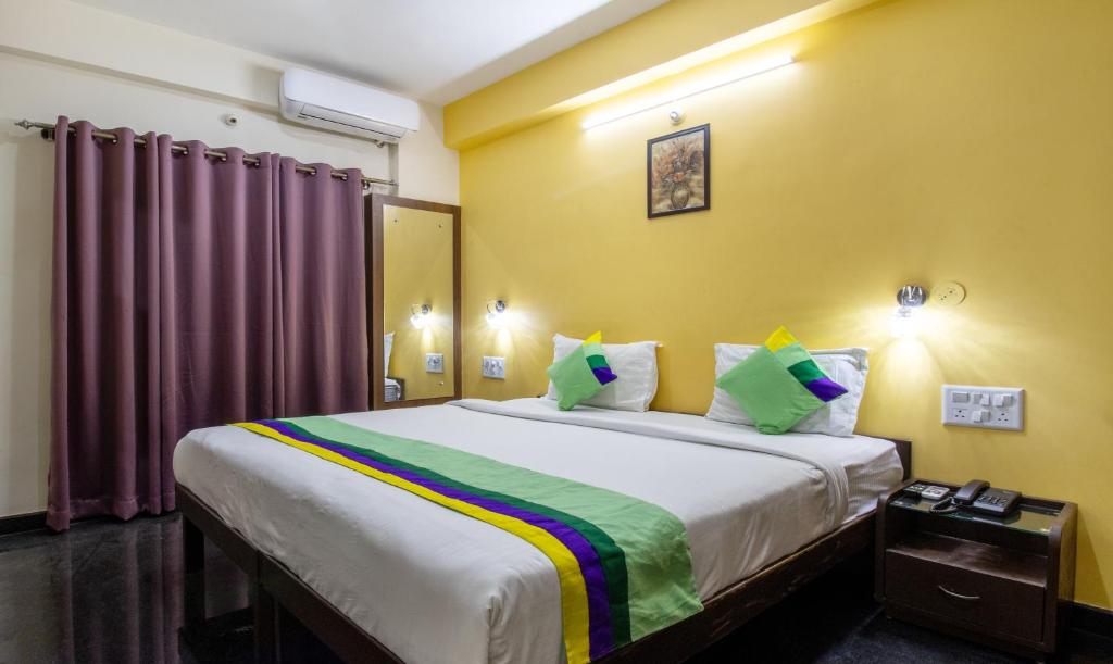 a bedroom with a large bed with yellow walls at Treebo RR Residency, Sanjay Nagar in Bengaluru
