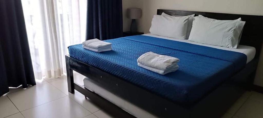 a bedroom with a bed with two towels on it at Carol Crosswinds Tagaytay in Cavite