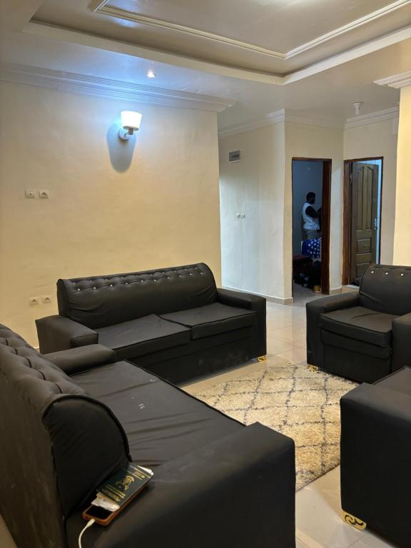 uma sala de estar com sofás pretos em Eden Meadows Estate (Dr. John) em Limbe