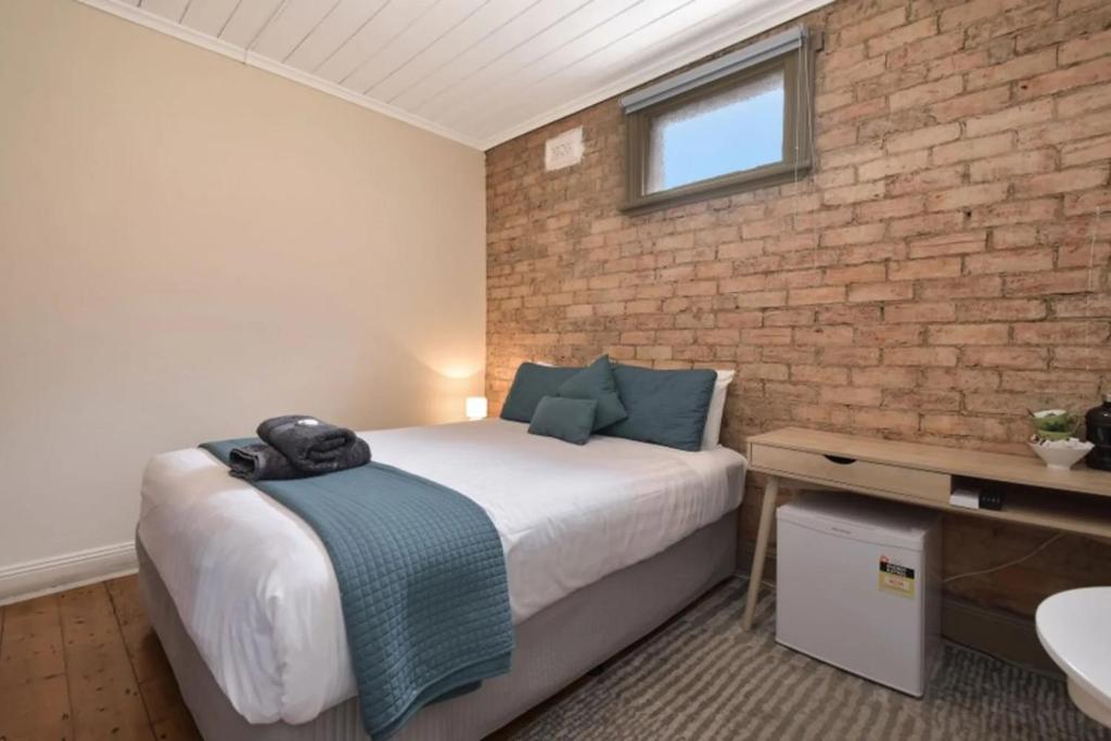 a bedroom with a bed and a brick wall at The Mess and Barracks in Ararat