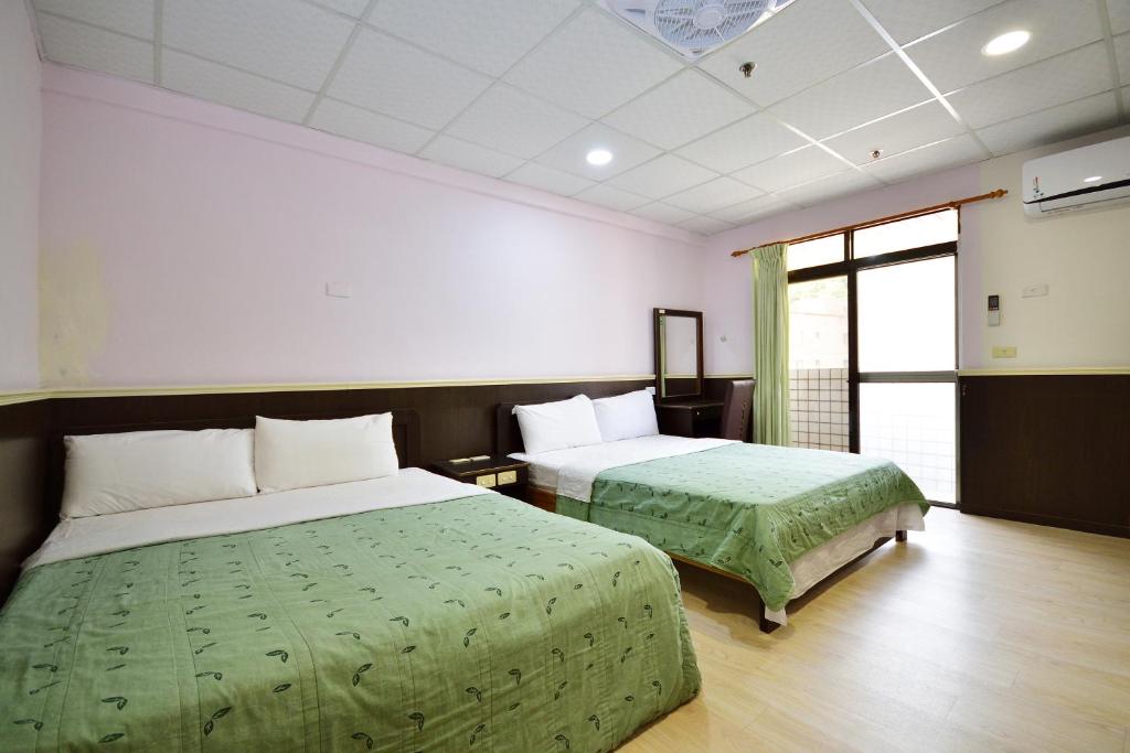ein Hotelzimmer mit 2 Betten und einem Fenster in der Unterkunft 知本溫泉-彩溱旅宿 in Wenquan