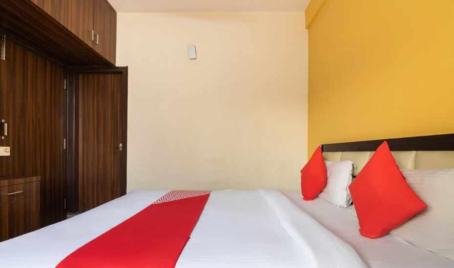 ein Schlafzimmer mit einem Bett mit roten Kissen darauf in der Unterkunft Royal INN HSRLayout in Bangalore