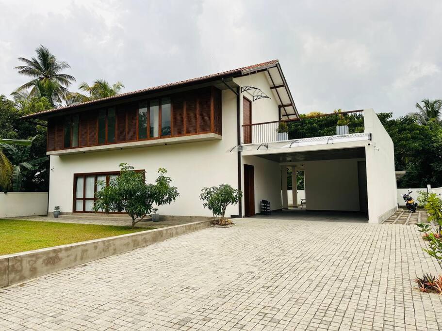 Una gran casa blanca con un patio enfrente. en Lake Round Luxury House en Kurunegala