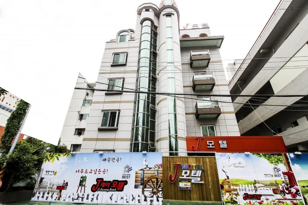 un edificio blanco alto con un cartel delante en J Motel, en Yeosu