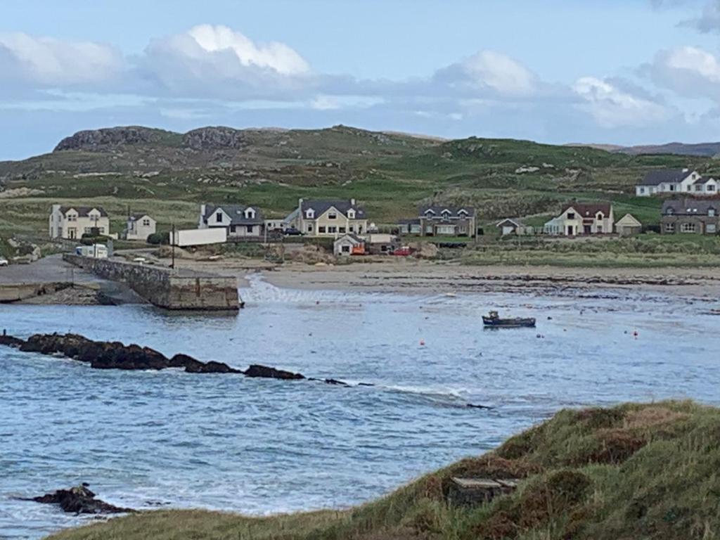 a group of houses on the shore of a body of water at Captivating 3-Bed Cottage in Port na Blagh in Port na Bláiche