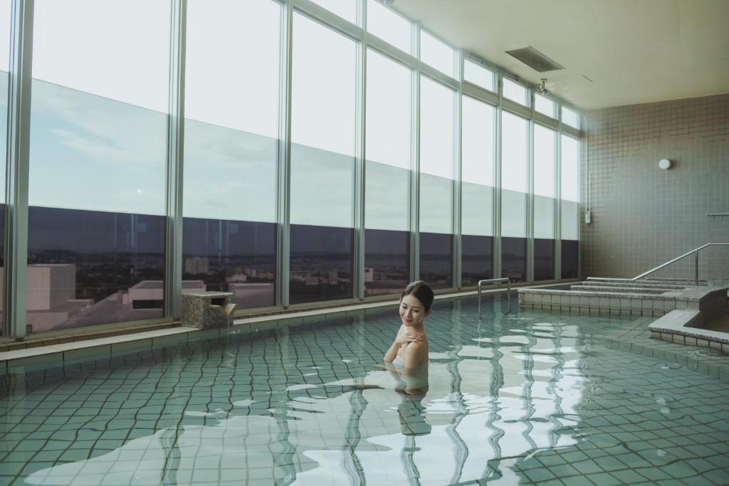 uma criança está sentada numa piscina em EM Wellness Kurashinohakko Lifestyle Resort em Kitanakagusuku
